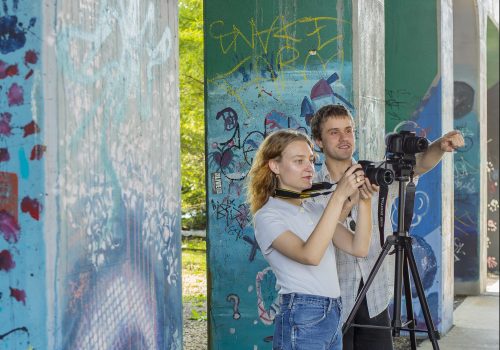 Students in front of graffiti art with cameras
